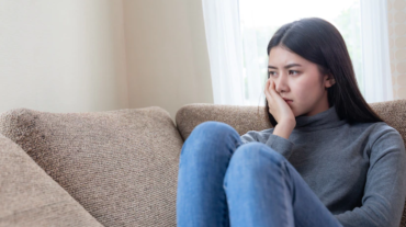 close-up-face-unhappy-asian-pretty-young-woman-sitting-alone-couch_1150-15513
